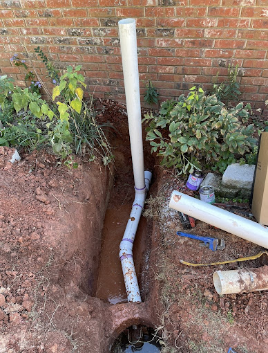 A drain in the ground next to a brick wall