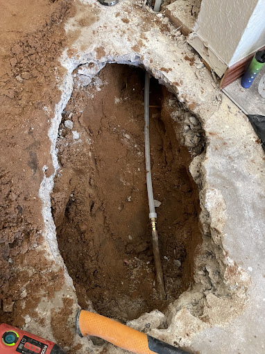 A hole in the ground with a wrench next to it