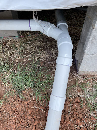 A white pipe is connected to a concrete structure