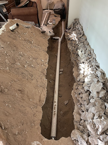 A pipe laying in the ground next to a wall