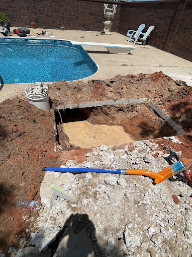 A pool being built with tools laying on the ground